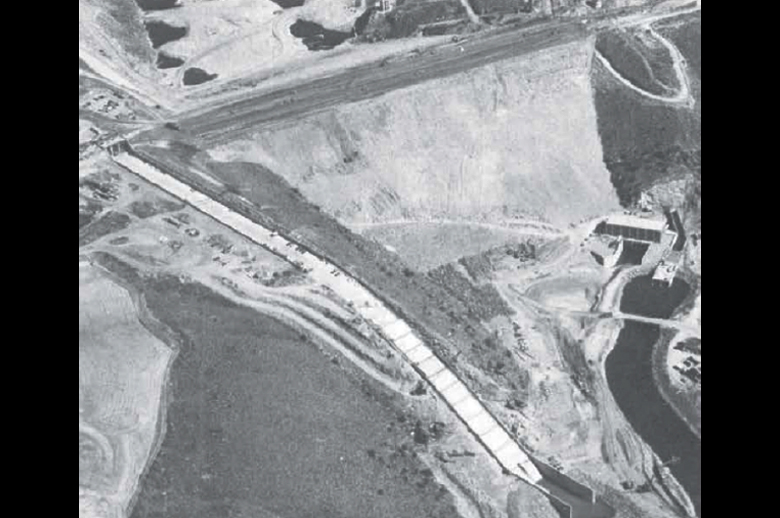 Figure 3. Aerial photo of Teton Dam as it was nearing completion, taken September 26, 1975, before the filling of the reservoir. Star marks approximate position near the right abutment where the leak began. Note the power and pumping station at the base of the dam. Source: After Teton